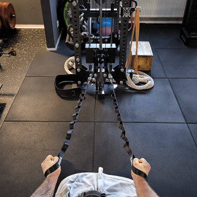 Zwei Hände halten Zugseile an einem Trainingsgerät im Fitnessstudio.
