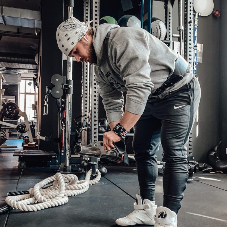 Mann trainiert im Fitnessstudio mit einem Seil und einer Gewichtsheberausrüstung.
